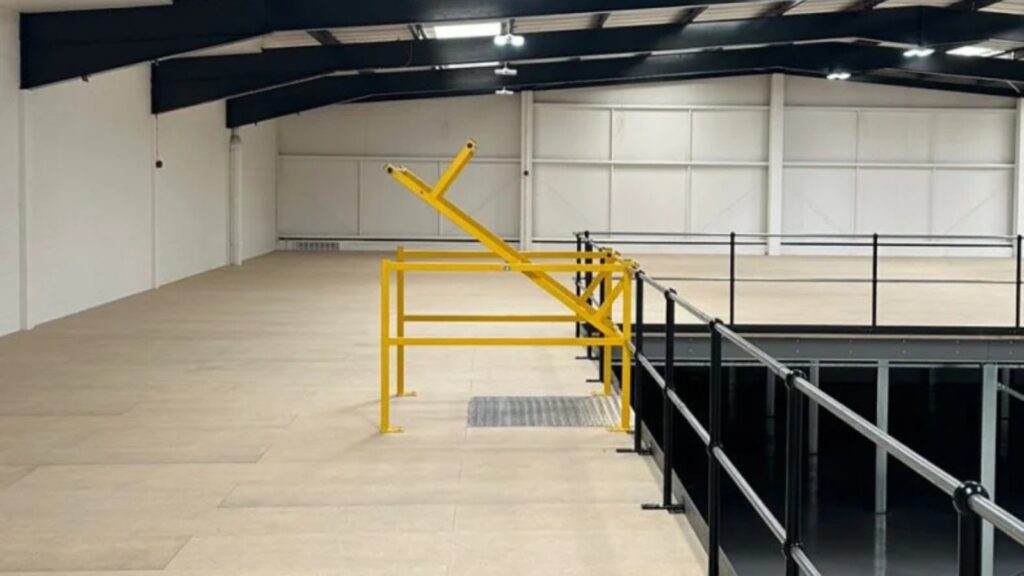 Empty warehouse mezzanine floor with safety pallet gate and railing, maximising usable storage space